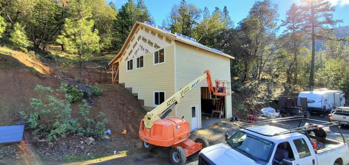 Two-story home mid-siding-installation with a boom lift on a Southern Oregon job site, Next Gen Contracting