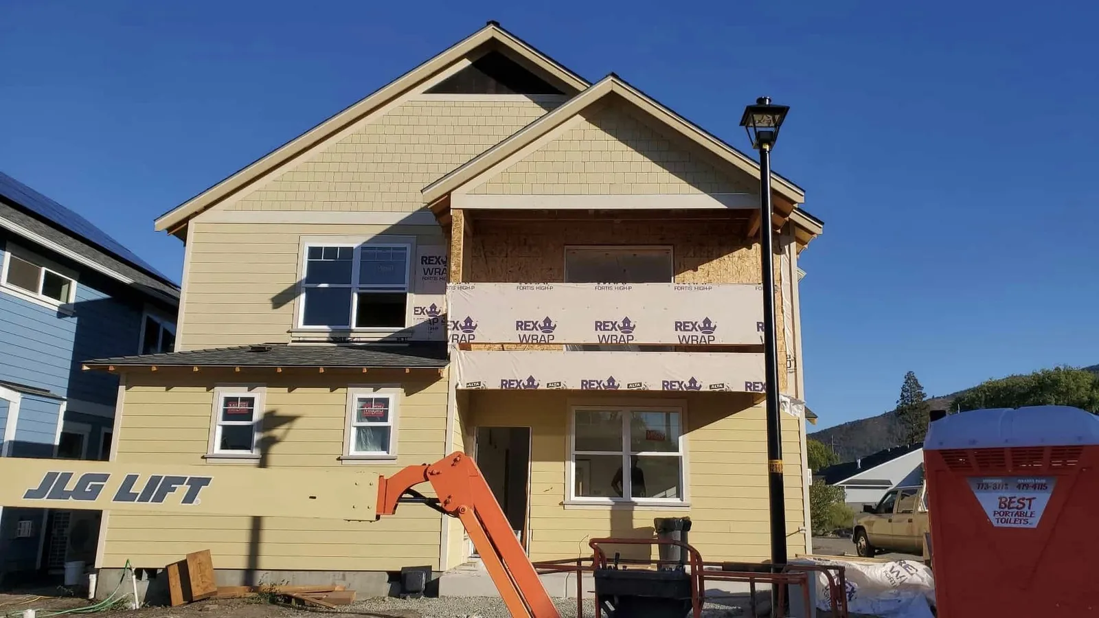 Two-story Southern Oregon home mid-siding-installation, new lap and shingle siding going up over house wrap